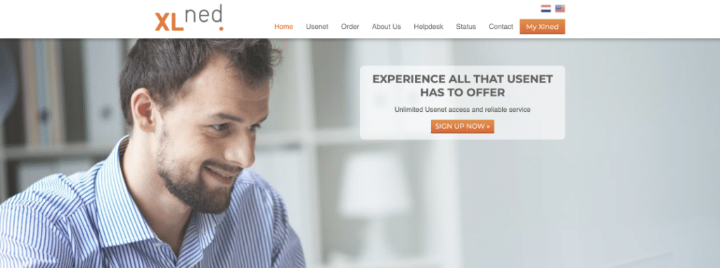 A man with short hair and a well-trimmed beard is smiling at his laptop.