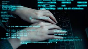 Person's hands typing on a black keyboard with green text overlaid on the image.