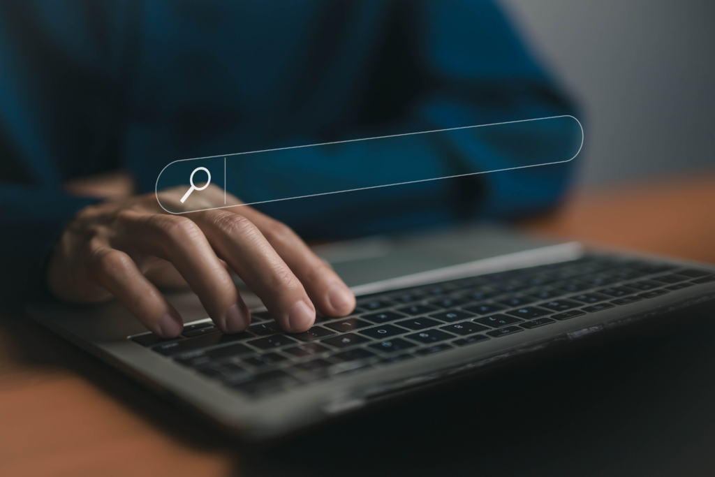 A search bar hovering over a black keyboard with a human hand typing on it, likely using one of the best NZB Indexers.