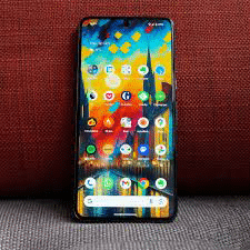 A Google Pixel 8 Pro standing on a couch with the screen on.