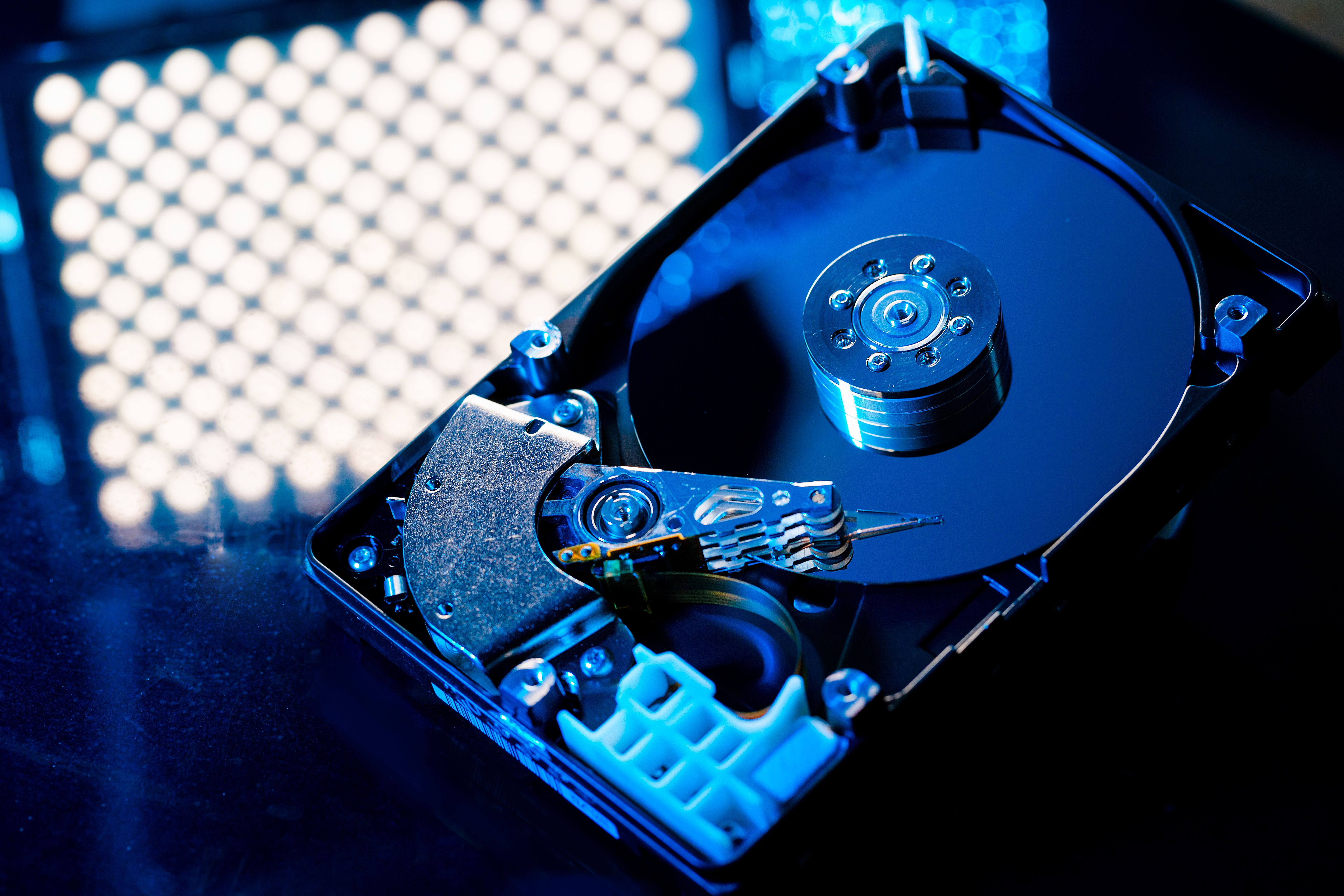 Closeup of a hard disk drive on a black glass table reflecting the lights above it.